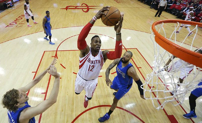 Houston Rockets' Dwight Howard (12) drives to the basket between Dallas Mavericks' Dirk Nowitzki, left, and Dallas Mavericks' Tyson Chandler, rights, during the first half in Game 1 in the first round of the NBA basketball playoffs Saturday, April 18, 2015, in Houston. (AP Photo/David J. Phillip)