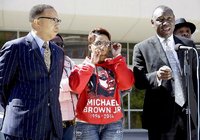 Lesley McSpadden, mother of Michael Brown, wipes her eye as she is flanked by her attorneys Anthony D. Gray, left, and Benjamin L. Crump, right, during a news conference Thursday, April 23, 2015, in Clayton, Mo. The parents of Michael Brown filed a wrongful-death lawsuit Thursday against the city of Ferguson over the fatal shooting of their son by a white police officer, a confrontation that sparked a protest movement across the United States. (AP Photo/Jeff Roberson)