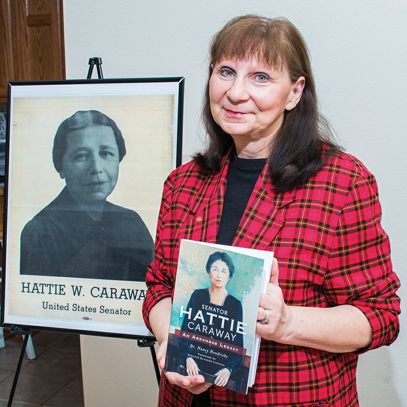 Nancy Hendricks of Hot Springs Village has written a book about Hattie Caraway, Arkansas’ first woman United States senator. Shown here with a copy of her book and a poster of Caraway, Hendricks travels the state promoting the book, which was published in 2013.