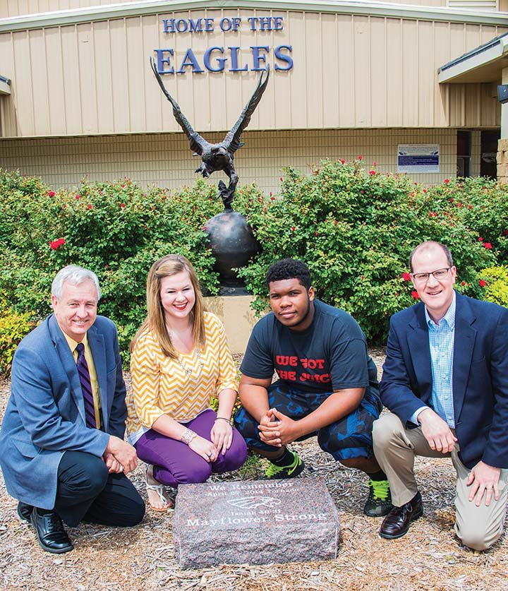 Mayflower School District Superintendent John Gray, from left, kneels with Mayflower High School Student Council President Ashley Raney, senior Stephen Fuller and the Rev. David Fox as they get ready for the unveiling of a commemorative stone on Monday, the one-year anniversary of the April 27, 2014, tornado that hit the city. A ceremony is set for 7:30 a.m. Monday in front of the gymnasium.