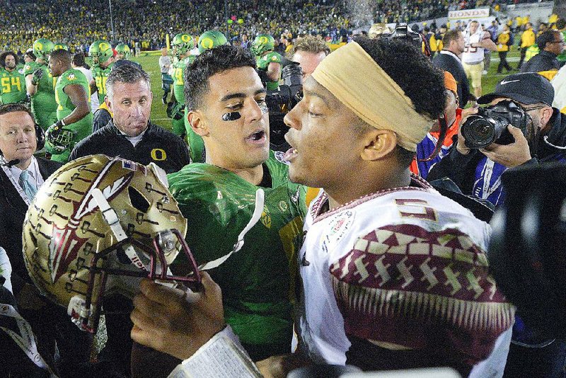 FILE - In this Jan. 1, 2015, file photo, Oregon quarterback Marcus Mariota, center left, greets Florida State quarterback Jameis Winston after Oregon's win in the Rose Bowl NCAA college football playoff semifinal game in Pasadena, Calif. There will be several noticeable absences when the three-day draft starts Thursday night, including potential top picks. Winston, Mariota and Alabama wide receiver Amari Cooper all plan to skip the spotlight.  (AP Photo/Mark J. Terrill, File)