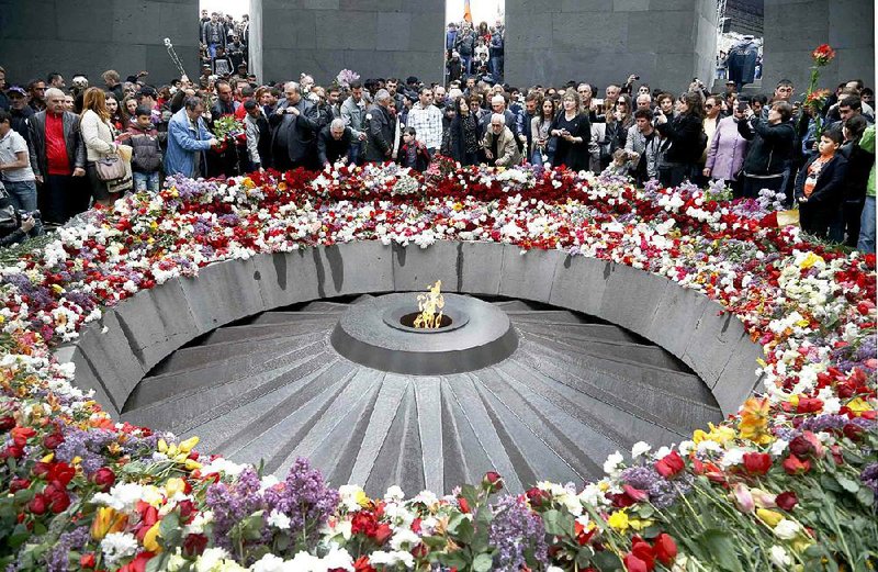 People lay flowers at a memorial to Armenians killed by the Ottoman Turks, as they mark the centenary of the mass killings, in Yerevan, Armenia, Friday, April 24, 2015. On Friday, Armenians mark the centenary of what historians estimate to be the slaughter of up to 1.5 million Armenians by Ottoman Turks, an event widely viewed by scholars as genocide. Turkey, however, denies the deaths constituted genocide and says the death toll has been inflated. (AP Photo/Sergei Grits)