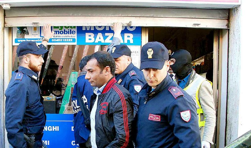 Italian police officers arrest a suspect in Olbia, Italy, Friday, April 24, 2015. Islamic extremists suspected in a bomb attack in a Pakistani market that killed more than 100 people had also planned an attack against the Vatican in 2010 that was never carried out, an Italian prosecutor said Friday. Police arrested nine suspects related to the probe Friday throughout Italy. Another nine were being sought, three of whom were believed to still be in the country. (AP Photo/Antonio Satta)