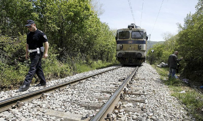 A police officer walks along the rail tracks north of the central Macedonian town of Veles, on Friday, April 24, 2015 near where 14 migrants were killed by a train while walking along the tracks. Fourteen migrants believed to be from Afghanistan and Somalia who were heading north toward the European Union were killed by an express train as they walked along tracks in central Macedonia Thursday night, police said Friday. (AP Photo/Boris Grdanoski)