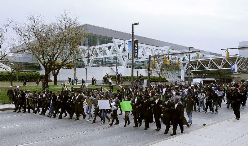 Marchers pass in front of the Baltimore Convention Center during a march to City Hall for Freddie Gray, Saturday, April 25, 2015 in Baltimore. Gray died from spinal injuries about a week after he was arrested and transported in a police van. (AP Photo/Alex Brandon)