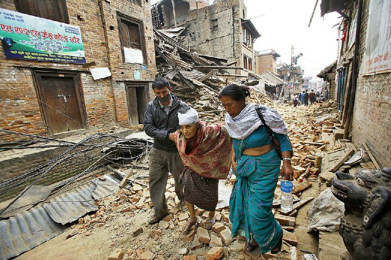 An elderly injured woman is taken to her home after treatment in Bhaktapur near Kathmandu, Nepal, Sunday, April 26, 2015. A strong magnitude 7.8 earthquake shook Nepal's capital and the densely populated Kathmandu Valley before noon Saturday, causing extensive damage with toppled walls and collapsed buildings, officials said. (AP Photo/Niranjan Shrestha)