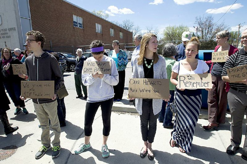 RETRANSMISSION TO CORRECT SPELLING OF NAME FROM PONTINOUS TO PONTIOUS - From left, David Pontious, Moira Pannepacker, Kelly Lussier and Juliana Restrivo, hold support signs for Freddie Gray outside of Vaughn Greene Funeral Home, during his wake Sunday, April 26, 2015 in Baltimore. Gray died from spinal injuries about a week after he was arrested and transported in a police van. (AP Photo/Jose Luis Magana)