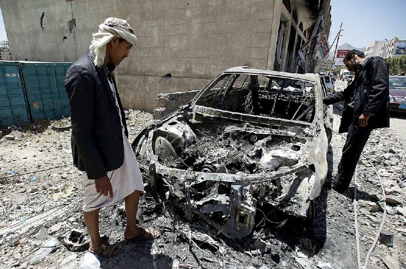 Men look at a car destroyed by a recent Saudi-led airstrike  in Yemen's capital, Sanaa,  Saturday, April 25, 2015.  With combatants fighting in neighborhoods and Saudi-led coalition warplanes pounding Iran-backed rebels from the sky, Yemen's war is wreaking a particularly bloody toll among civilians: more than 550 have been killed in the past month, including 115 children, the U.N. said Friday. (AP Photo/Hani Mohammed)