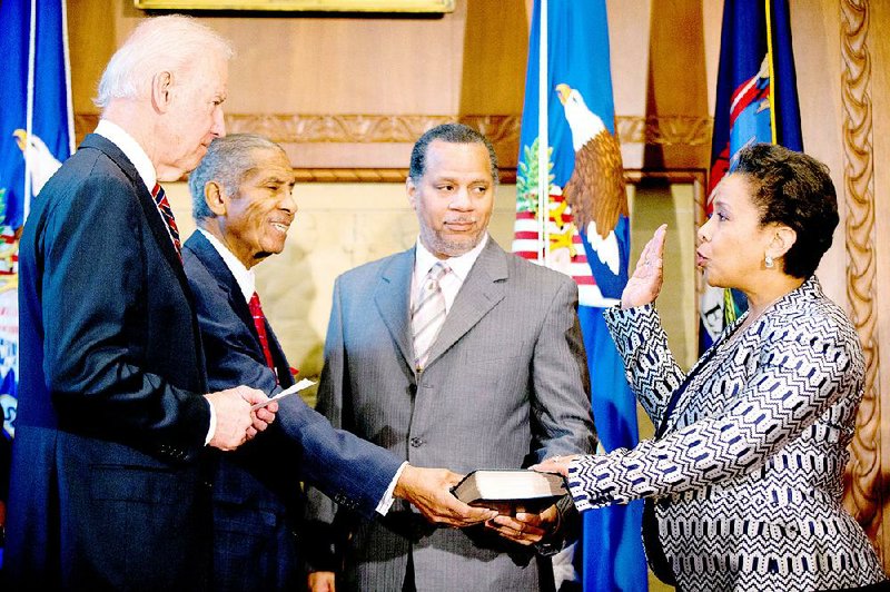 Vice President Joe Biden, accompanied by Loretta Lynch's father Lorenzo Lynch, second from left, and Loretta Lynch's husband Stephen Hargrove, second from right, administers the oath of office to Loretta Lynch as the 83rd Attorney General of the U.S., Monday, April 27, 2015, during a ceremony at the Justice Department in Washington. (AP Photo/Andrew Harnik)