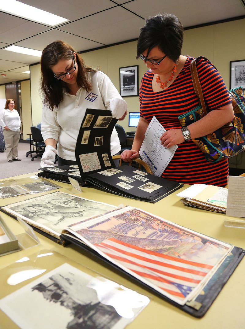 4/27/15
Arkansas Democrat-Gazette/STEPHEN B. THORNTON
Arkansas History Commission archival assistant Crystal Shurley, left, helps Erin Fehr, look through a scrapbook created by a World War I Veteran on display during the commission's 110th anniversary celebration Monday in Little Rock.