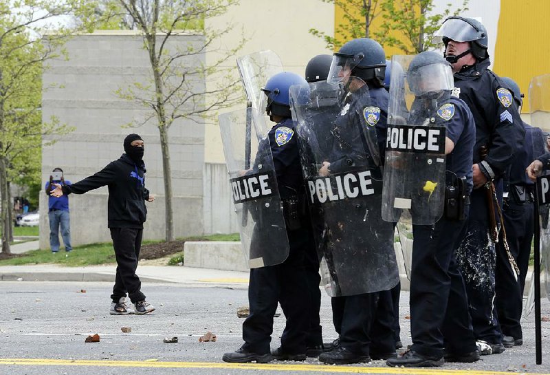 A demonstrator taunts police as they respond to thrown objects, Monday, April 27, 2015, after the funeral of Freddie Gray in Baltimore. Gray died from spinal injuries about a week after he was arrested and transported in a Baltimore Police Department van. (AP Photo/Patrick Semansky)