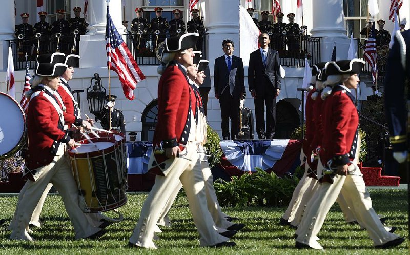 President Barack Obama and Japanese Prime Minister Shinzo Abe watch as the United States Army Old Guard Fife and Drum Corps march past during a state arrival ceremony Tuesday on the South Lawn of the White House in Washington.