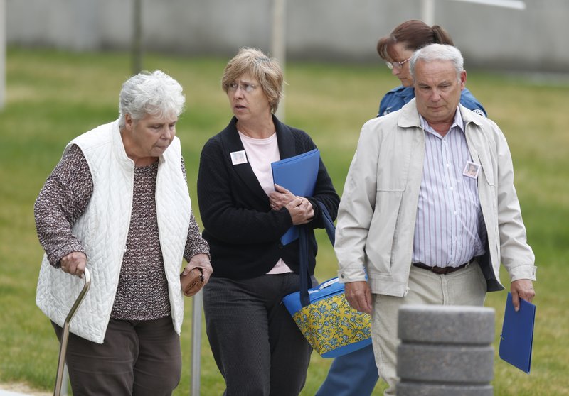Wearing squares on their coats featuring the photograph of 6-year-old Veronica Moser-Sullivan, who was the youngest victim of the massacre at the theatre in Aurora, Colo., attendees are escorted out of the courthouse at the conclusion of the opening day of the trial for theatre shooting suspect James Holmes Monday, April 27, 2015, in Centennial, Colo. The trial will determine if Holmes will be executed, spend his life in prison or be committed to an institution as criminally insane.