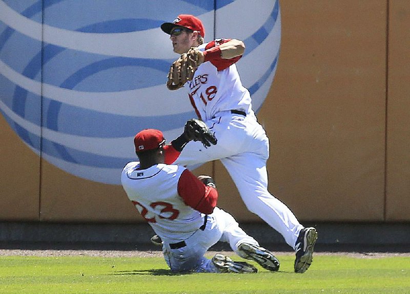 Arkansas Travelers left fielder Kentrail Davis slides under center fielder Chad Hinshaw to avoid a collision as they both went for a fly ball in the outfield Wednesday at Dickey-Stephens Park in North Little Rock. Hinshaw caught the ball. 
