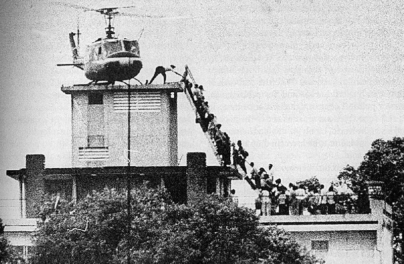 A member of the CIA helps evacuees up a ladder onto an Air America helicopter on the roof of 22 Gia Long Street April 29, 1975, shortly before Saigon fell. 