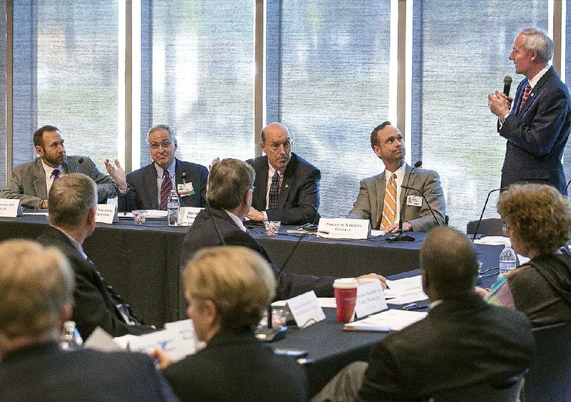 Gov. Asa Hutchinson (standing) describes the task ahead for members of the Governor’s Advisory Council on Medicaid Reform — from left, Arkansas Department of Health Director Nate Smith, University of Arkansas for Medical Sciences Chancellor Dan Rahn, Department of Human Services Director John Selig, Arkansas Surgeon General Greg Bledsoe and other members of the council during its first meeting Thursday morning at UAMS. 