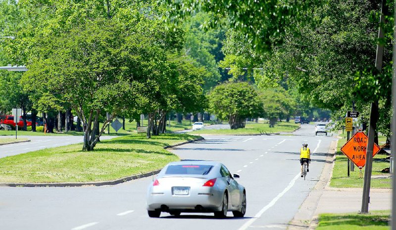 A cyclist travels down Riverfront Drive on Thursday in Little Rock’s Riverdale neighborhood. The city must decide today whether to apply for a federal grant that would allow the city to widen the bike lanes on the road and reduce vehicle lanes. 