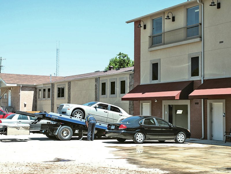 NWA Democrat-Gazette/ANTHONY REYES &#8226; @NWATONYR A tow truck unloads a Chrysler 300 into the bay at ahe Springdale Police building Thursday in Springdale. Three women were arrested in connection with vehicle thefts from car lots in Springdale. They were described as arriving in a Chrysler 300.