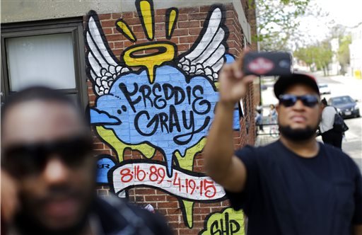 J.R. White, right, takes a selfie in front of a mural that was painted at the site of Freddie Gray's arrest, Saturday, May 2, 2015, in Baltimore, as protesters prepare to march to City Hall. Six police officers were charged Friday with felonies ranging from assault to murder in Gray's death. In announcing the charges, State's Attorney Marilyn Mosby said police had no reason to stop or chase Gray in the first place when they confronted him on April 12. He died of injuries on April 19.