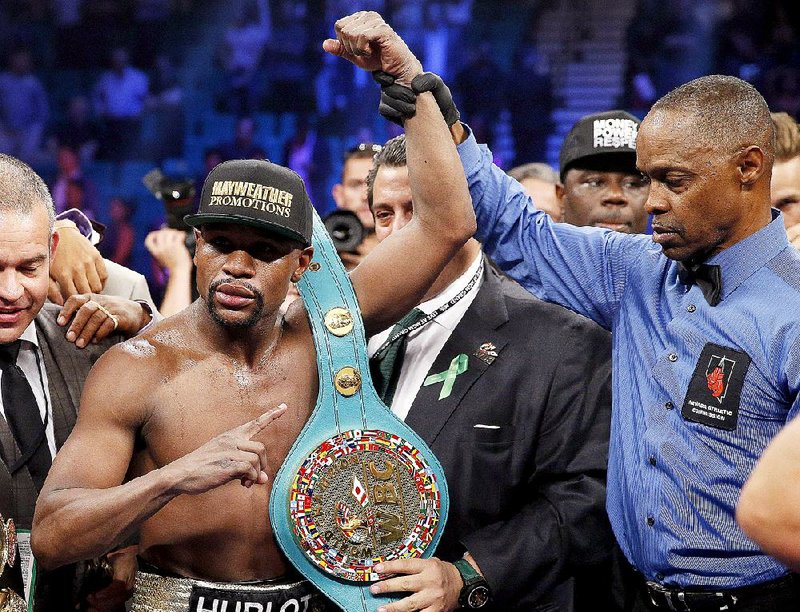 Floyd Mayweather Jr., celebrates his victory over Manny Pacquiao, from the Philippines, with the champion's belt following their welterweight title fight on Saturday, May 2, 2015 in Las Vegas. At right is referee Kenny Bayless. (AP Photo/John Locher)