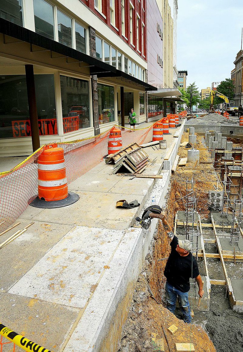 4/21/15
Arkansas Democrat-Gazette/STEPHEN B. THORNTON
Construction worker Shane Kelley, bottom right, grabs a tool belt as he works on a streetscaping project in front of the Main Street Lofts project in the former Arkansas Building, top left,  Tuesday in the 500 block of Main Street in downtown Little Rock. 