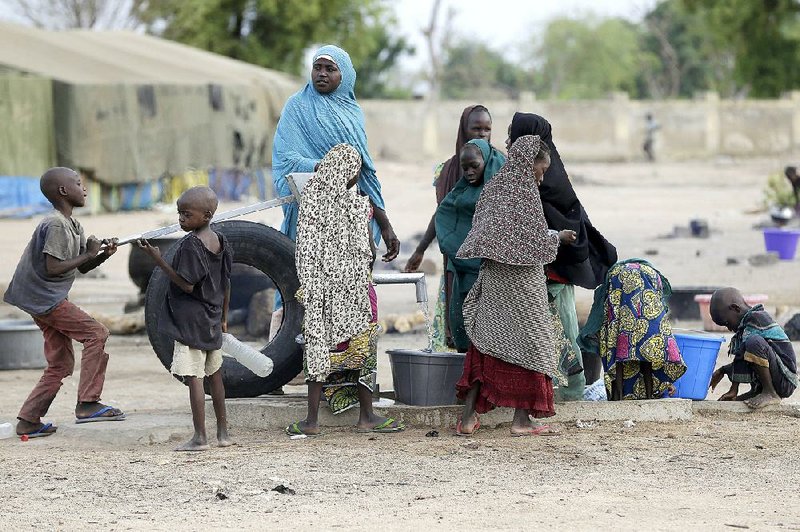 Women and children fetch water at a refugee camp in Yola, Nigeria, Sunday, May 3, 2015, after they were rescued by Nigerian soldiers from captivity by Boko Haram fighters.  Some survivors told The Associated Press on Sunday, that Islamist extremists stoned some of their captives to death as Nigeria's military approached to rescue the women, for some after more than a year in the hands of Nigeria's homegrown Islamic extremists. ( AP Photo/Sunday Alamba)