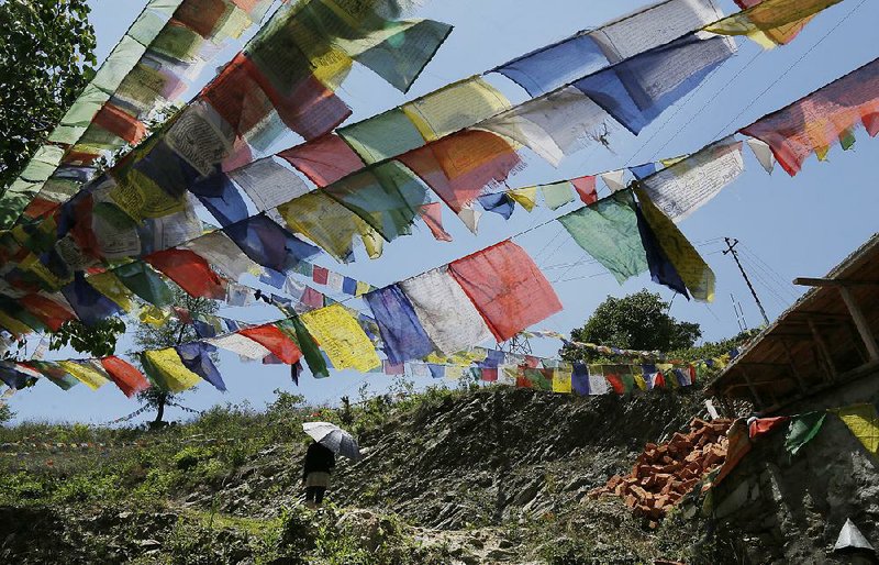 A Buddhist walks under prayer flags after paying her respects for those who died in last week's massive earthquake at the Nedyon Unphong Thapchyo Monastery in Bidur, Nuwakot District, Nepal, Monday, May 4, 2015. Celebrations of Buddha’s birthday in Nepal were muted on Monday, as the country’s faithful turned their prayers to loved ones lost in the earthquake and worries that the tragedy may have marked the beginning of a much larger reckoning. (AP Photo/Wally Santana)