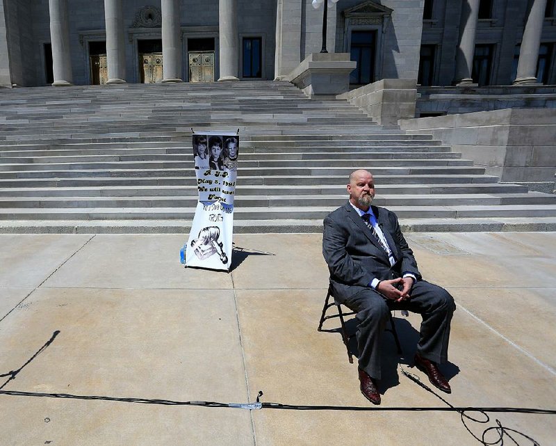 John Mark Byers, adoptive father of Christopher Byers, sits at the state Capitol on Tuesday during an event calling for justice in the slayings of 8-year-olds Christopher, Stevie Branch and Michael Moore (photos on poster, left) in West Memphis in 1993. 