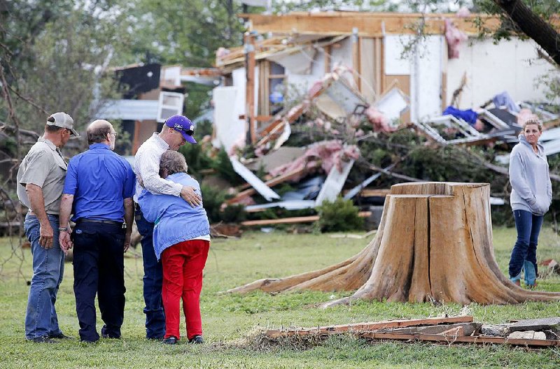 Charmaine Foraker’s son Harlan hugs her Wednesday as she and her other son, Craig (second from left), arrive at the family farmstead near Bentley, Kan., after a tornado swept through.