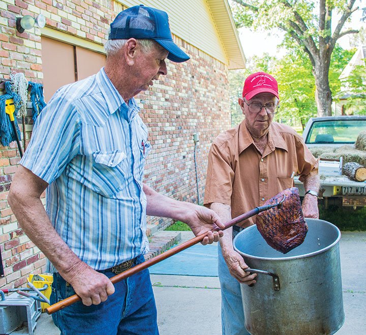 Max Nutt, left, and his brother Lee Nutt pull meat from the smoker as they prepare for the St. Boniface Catholic Church Bazaar, to be held from 11 a.m. to 3 p.m. May 17 at the church in the New Dixie community. The bazaar, the only fundraiser for the church, will include games, a raffle, a silent auction, arts and crafts, and a meal.
