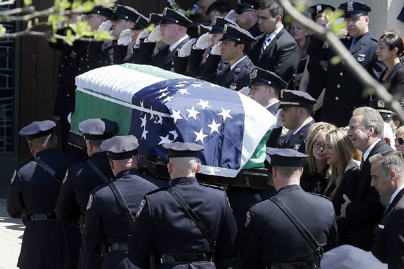 The family of New York City police officer Brian Moore, right, watch as his casket is carried into the St. James Roman Catholic church for his funeral mass, Friday, May 8, 2015, in Seaford, N.Y. The 25-year-old died Monday, two days after he was shot in Queens.  (AP Photo/Mary Altaffer)