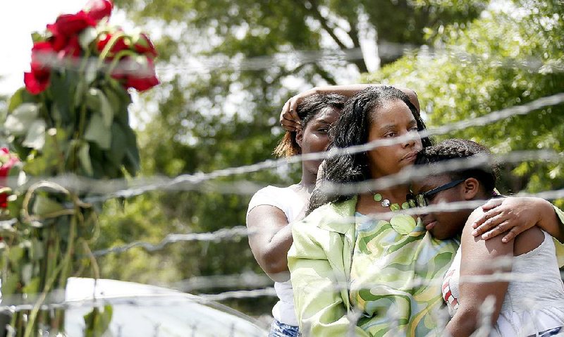 Alberta Harris (center), Waynetta Theodore (left) and Christiena Preston console one another Sunday as they pay their respects at a makeshift memorial near the site where two police officers were killed in Hattiesburg, Miss. 