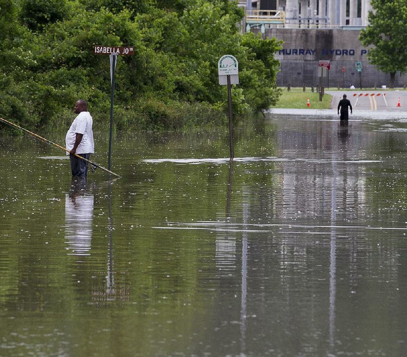 Deon Spencer fishes Tuesday in a flooded area of Cook’s Landing Road in North Little Rock. Farther downriver, low areas around the Clinton Presidential Center are predicted to flood by this afternoon.