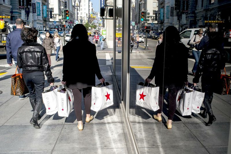 Shoppers carry Macy’s Inc. bags in San Francisco in January. A strong dollar slowed spending by overseas visitors at Macy’s stores in the first quarter, contributing to a 13 percent decline in profit. 