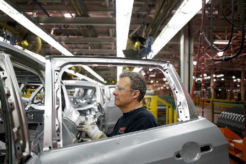 A worker inspects the metal frame of a Ford Escape sport utility vehicle during production last month at the Ford Motor Co. assembly plant in Louisville, Ky. 