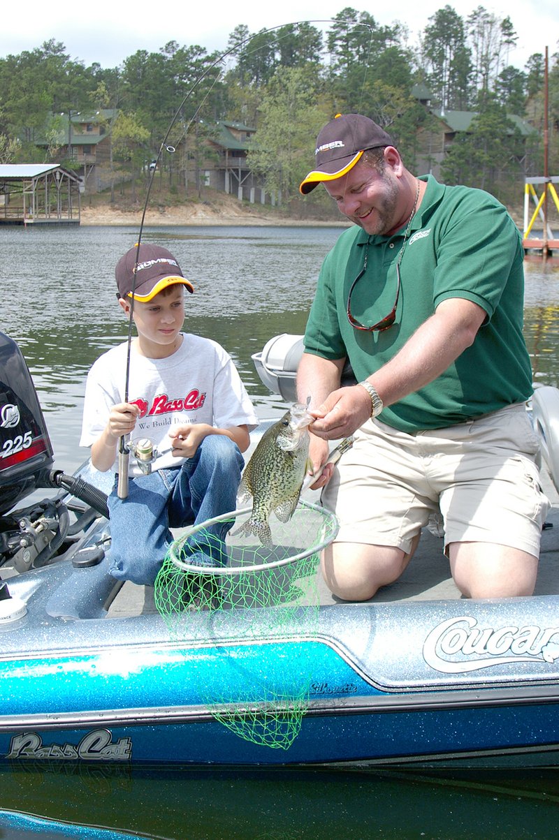 Chris Elder of Mount Ida nets a nice Lake Ouachita crappie for his son Dustin. A fishing trip with Dad or Mom can be great fun, especially if the adult lets the child do the fishing while the parent assists.