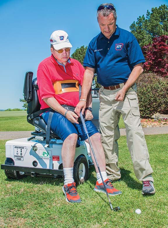 Randy Hays of Bryant, left, receives instruction from Arkansas Freedom Fund Director Mark Leonard, also of Bryant, on turning his chair to hit a golf ball without getting out of a handicapped golf cart. The special golf cart was provided for Hays during the Arkansas Freedom Fund Golf Scramble at the Diamante Country Club in Hot Springs Village.
