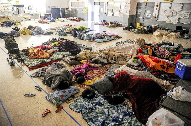 People taking shelter from raging Typhoon Dolphin try to sleep on the floor of an elementary school Friday in Dededo, Guam. 