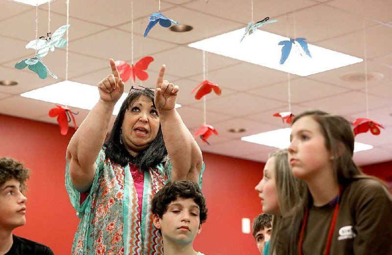 Vilonia Middle School teacher Linda Knapp describes a project hanging from the school’s ceiling Wednesday. Hundreds of butterflies represent the estimated 6 million Jews who died during the Holocaust.