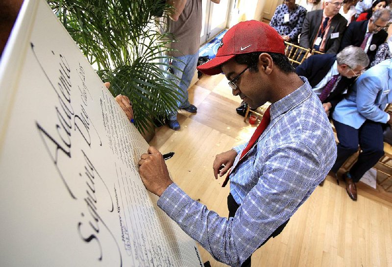 Little Rock School District senior Dhruba Dasgupta signs his name Monday afternoon during an academic signing day ceremony at the Governor’s Mansion. Dasgupta will be attending the University of Arkansas at Fayetteville.