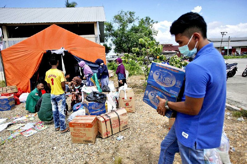 An Acehnese man carries boxes of mineral water to be distributed to ethnic Rohingya and Bangladeshi migrants at a temporary shelter in Langsa, Aceh province, Indonesia. Boatloads of more than 2,000 migrants ethnic Rohingya Muslims fleeing persecution in Myanmar, and Bangladeshis trying to escape poverty landed in Indonesia, Malaysia and Thailand last spring. Aid groups estimate that thousands more are stranded at sea after a crackdown on human traffickers prompted captains and smugglers to abandon their human cargo.