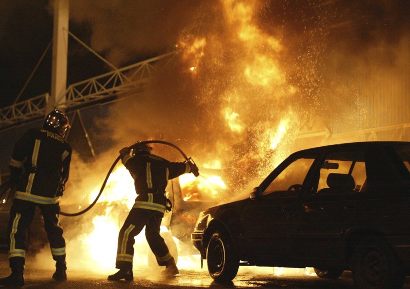 In this Nov. 8, 2005 file photo, firefighters work to extinguish burning cars set on fire by rioters in Gentilly, south of Paris, France. Two young boys were electrocuted in a power substation in Clichy-sous-Bois, while hiding from police on Oct. 27, 2005. 