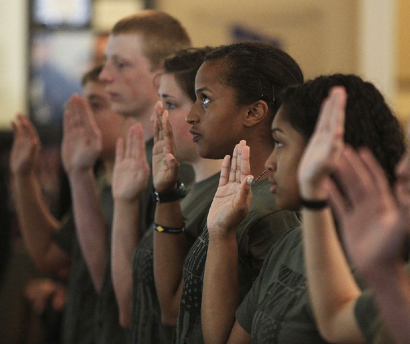 New Arkansas National Guard recruits, including Holly Eichelberger (second from right) of Hot Springs and Tyrah Colbert (right) of Morrilton, take the National Guard Oath of Enlistment on Tuesday during a ceremony at the MacArthur Museum of Arkansas Military History in Little Rock. 
