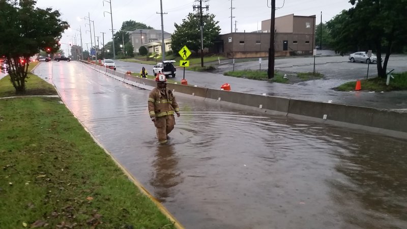A firefighter walks through a flooded stretch of LaHarpe Boulevard Wednesday morning in downtown Little Rock.