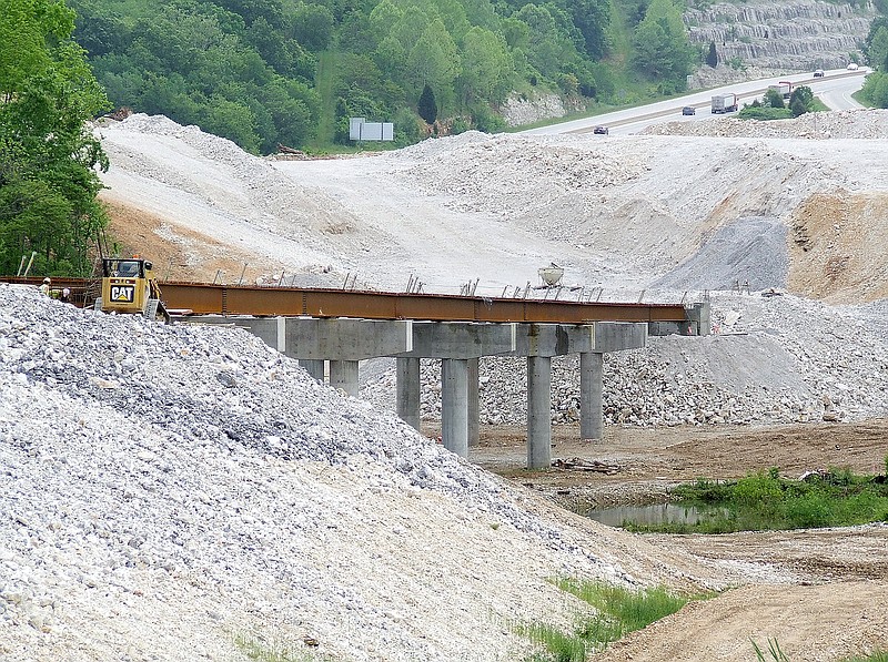 The Weekly Vista/Tom A. Throne Girders are going up on a bridge as part of the Bella Vista Bypass east of Peach Orchard Road. Drivers along I-49 can be seen in the background.