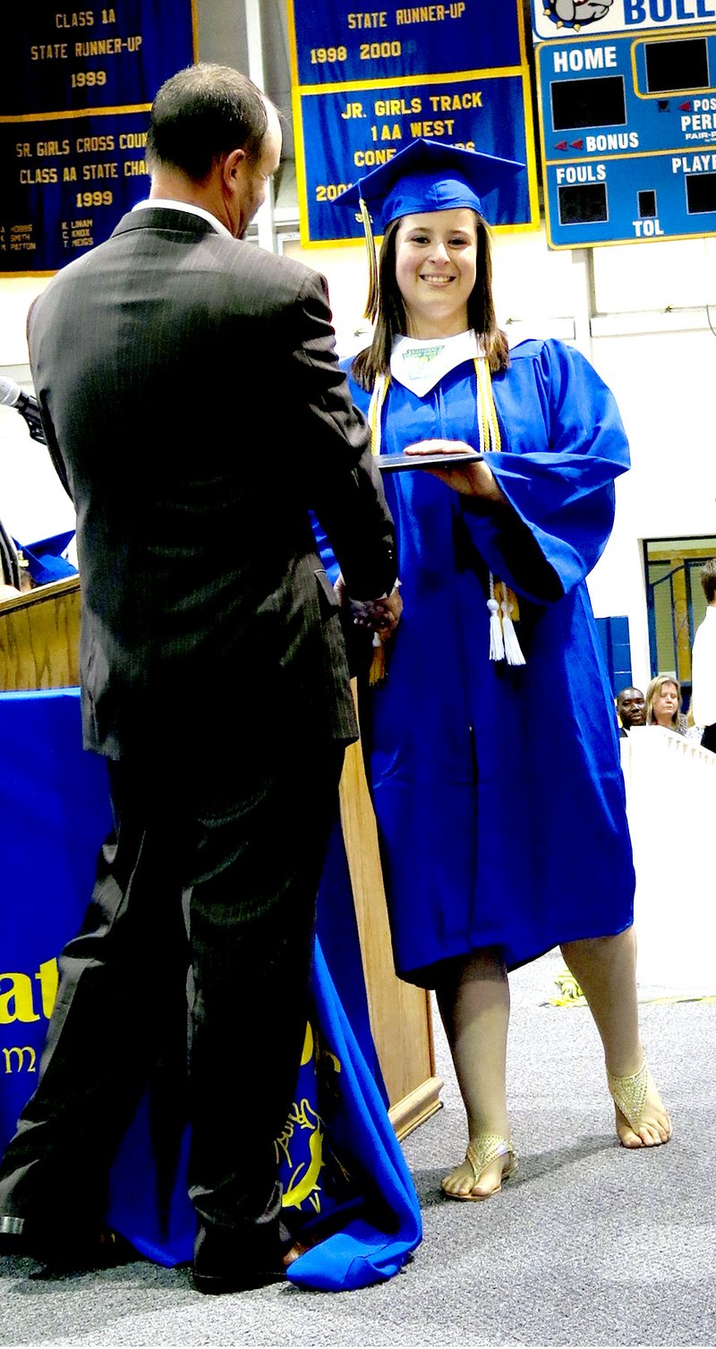 Photos by Mike Eckels Jaquelin Vargas smiles as a family member takes a picture while she receives her diploma from school board member Kevin Smith during the 2015 Decatur High School graduation ceremony at Lloyd Peterson Gym in Decatur on May 15. Vargas was the last member of the 2015 class to receive a diploma.