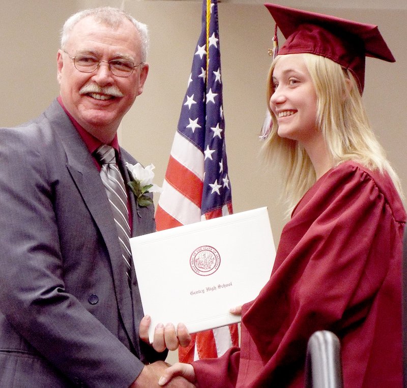Photos by Randy Moll Aja Fincher smiles for a photo while she receives her diploma from Jim Barnes, Gentry School Board president, during graduation ceremonies at the Bill George Arena in Siloam Springs on Saturday night.