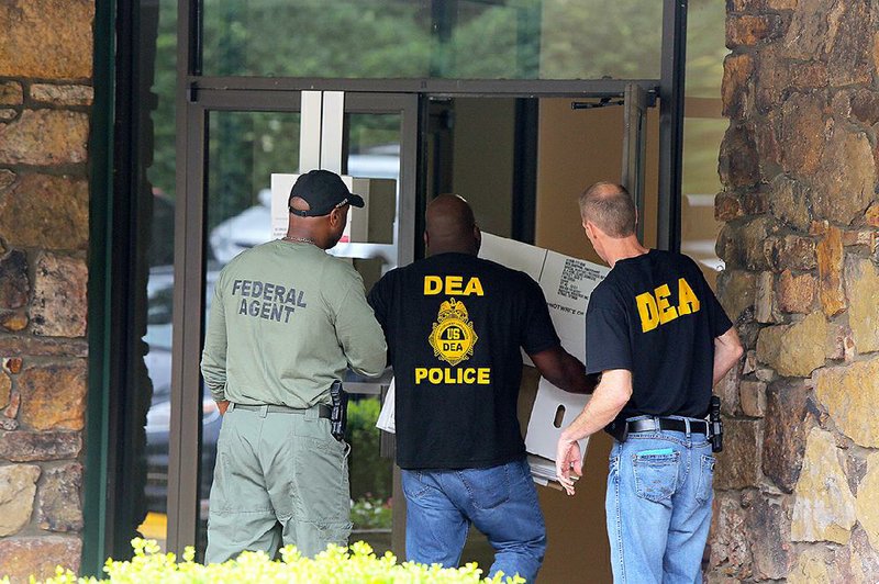 U.S. Drug Enforcement Administration officers carry boxes into KJ Medical Clinic on Wednesday after they raided the west Little Rock offices.