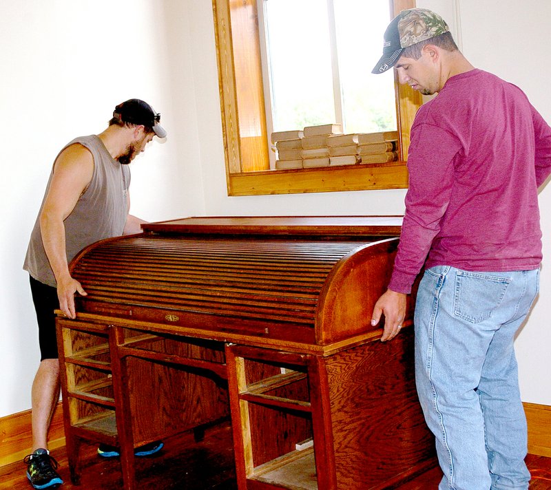 RICK PECK MCDONALD COUNTY PRESS Robby Towner (left) and James Story move an old rolltop desk into place for Saturday&#8217;s History Live! celebration at the Historic Courthouse On The Square.