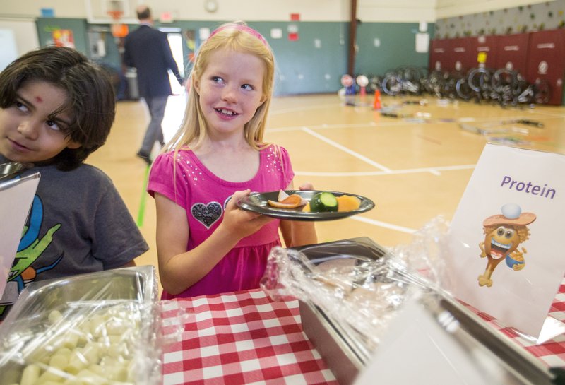 NWA Democrat-Gazette/JASON IVESTER Karloz Ortiz (left) and Rowan Sumers, both Asbell Elementary second-graders, sample snacks Wednesday during a nutrition lesson at the Fayetteville school.